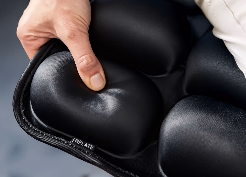 close up of a hand pressing the sondur travel cushion inflat