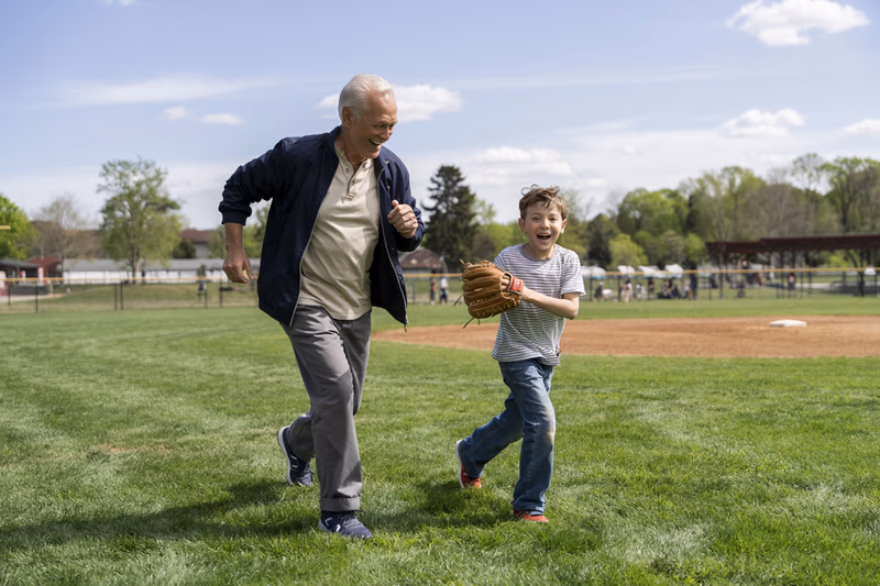 grandfather and grandson playing baseball on a sunny day