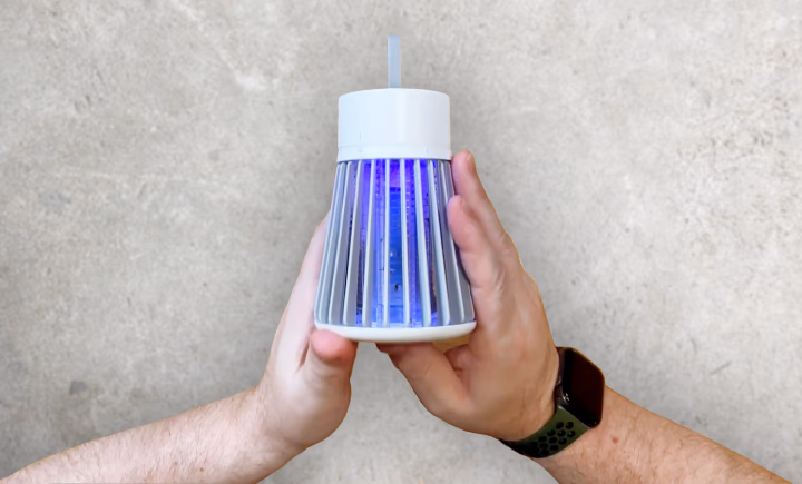 hands holding mosquito zapper with blue light