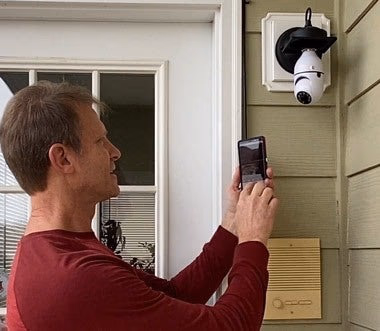 man checks outdoor security camera feed on smartphone