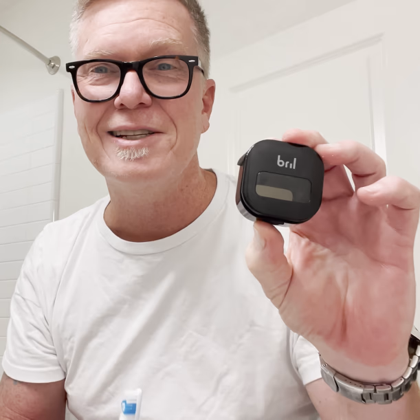 man holding a black bril toothbrush case with a clear window