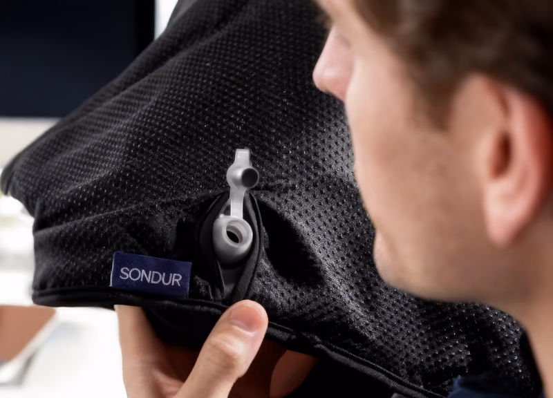 man holding the sondur travel cushion showing the brand labe
