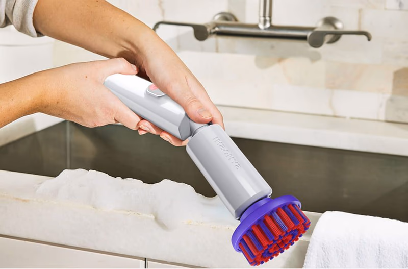 person using synoshi electric scrubber on sink edge
