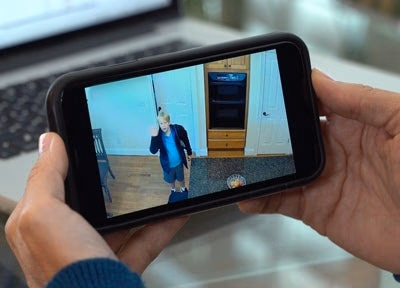 person viewing security camera feed of child waving on smart