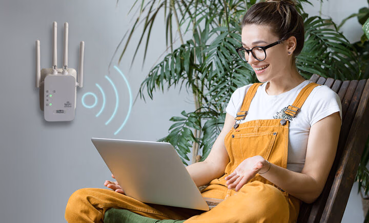 woman using laptop with wifi repeater on wall